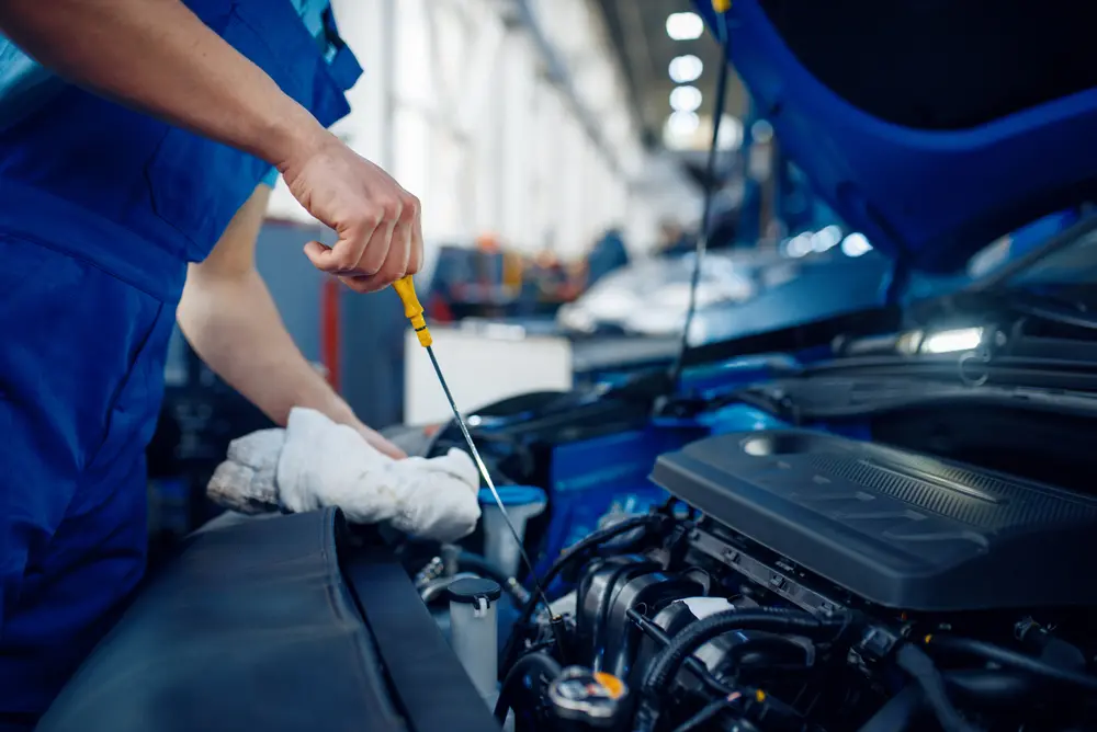 The worker checks the engine oil level – car maintenance service