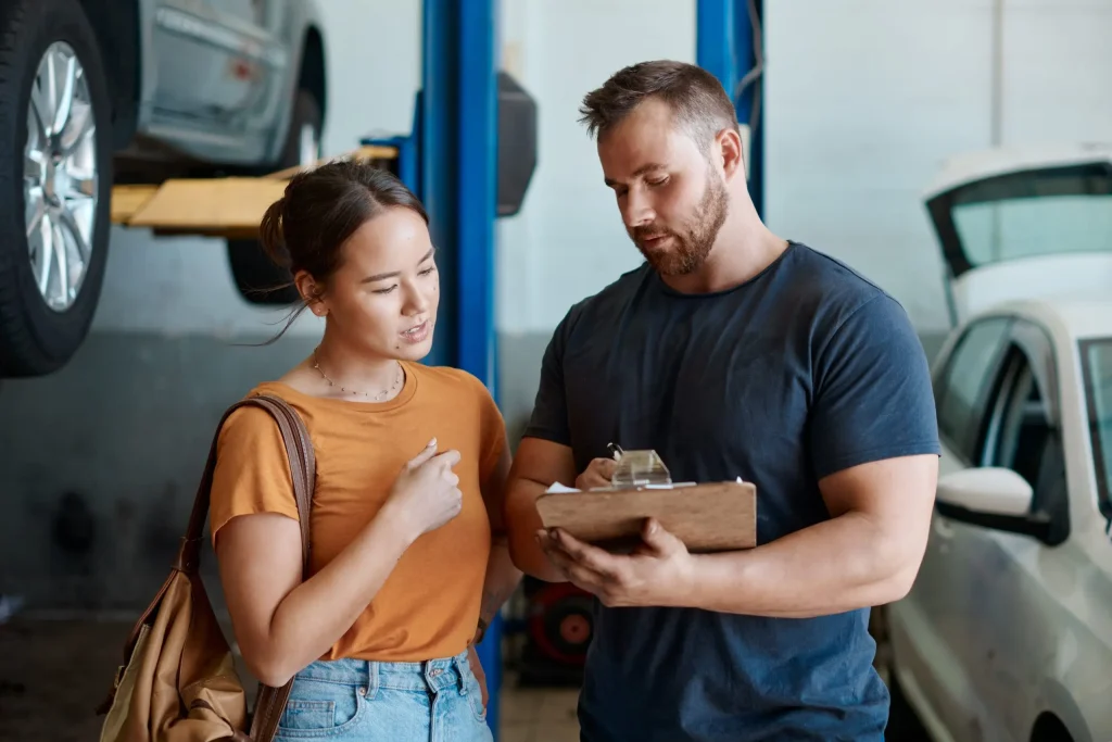 Auto repair specialist explaining preventive maintenance costs and service options to customer.